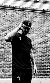 a black and white photo of a man standing in front of a brick wall